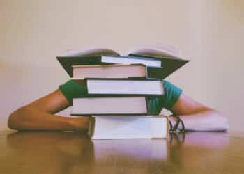 pexels-pixabay - étudiant derrière pile de livres - comment bien organiser ses révisions