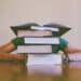 pexels-pixabay - étudiant derrière pile de livres - comment bien organiser ses révisions