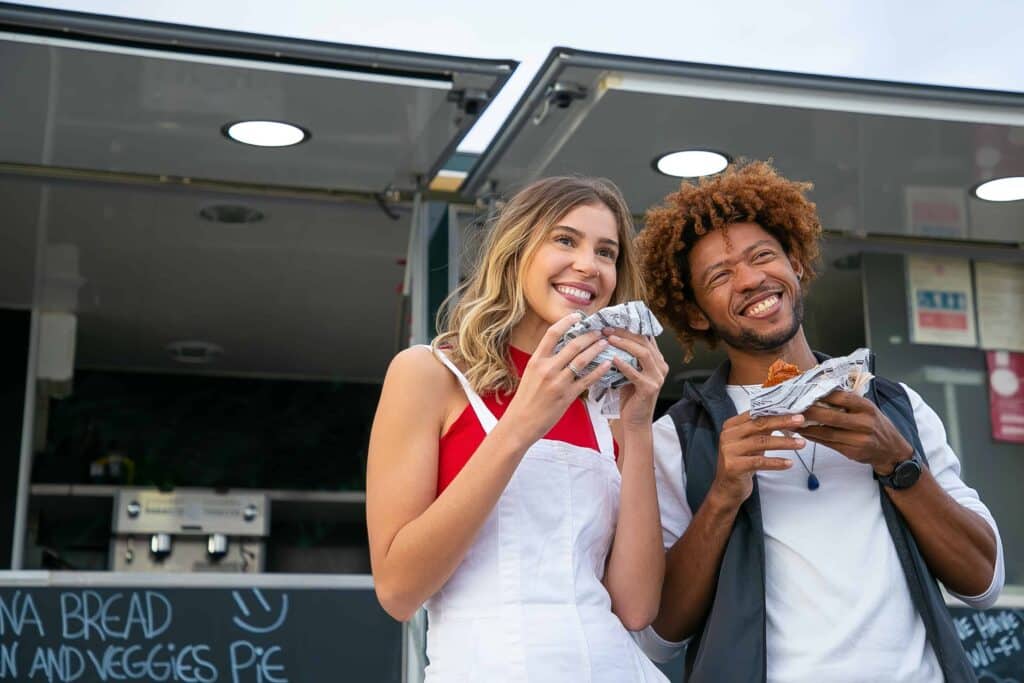 pexels-kampus-production-etudiants qui sourient et tiennent un hamburger - 5 adresses de Fast-food à Bruxelles à ne pas manquer