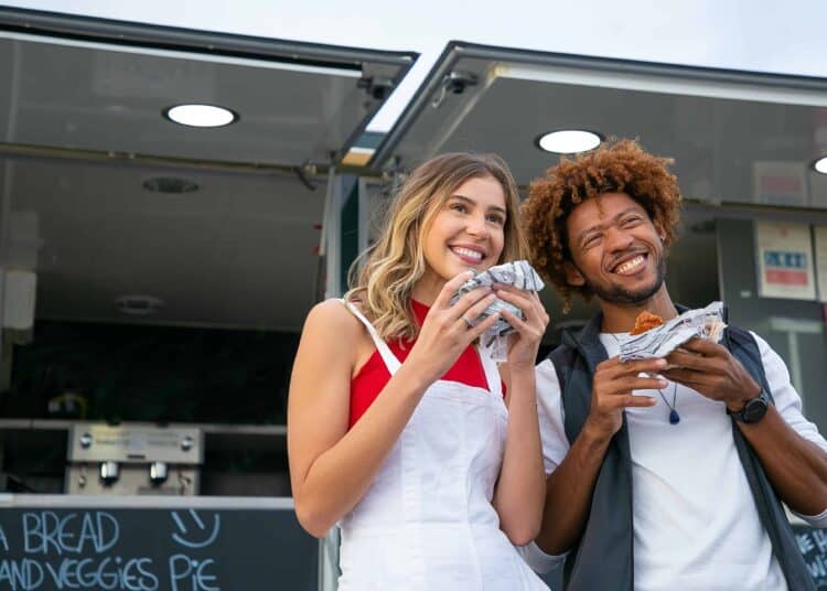 pexels-kampus-production-etudiants qui sourient et tiennent un hamburger - 5 adresses de Fast-food à Bruxelles à ne pas manquer