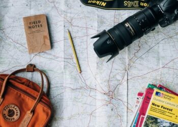 unsplash - Annie Spratt - appareil photo sac à dos bloc notes et livrets sur une grande carte - top 5 des city trips à faire absolument