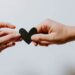 unsplash - Kelly Sikkema - deux mains qui tiennent un coeur en papier du bout des doigts - les mauvaises raisons de se remettre en couple