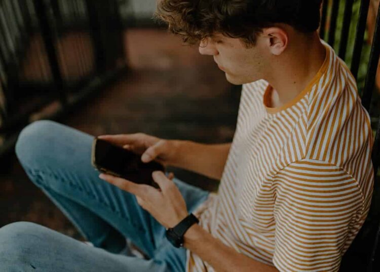 unsplash-hannah-busing - garçon sur son telephone - 7 memes qui resument bien ton mois de mai d'etudiant