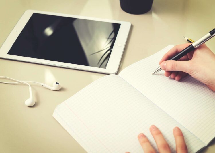 pixabay - photo mix company - une main qui écrit dans un cahier et une tablette - 5 avantages de l’évaluation continue