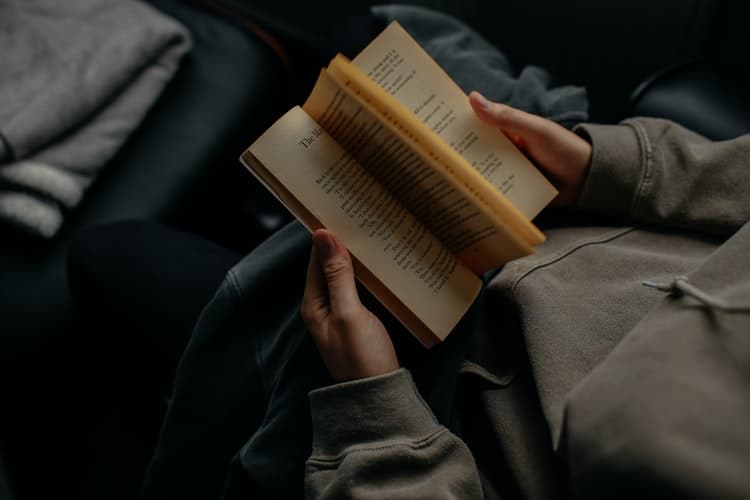 unsplash - Lilly Rum - personne qui lit un livre avec un sweat - top 5 des livres à lire pendant ta pause blocus