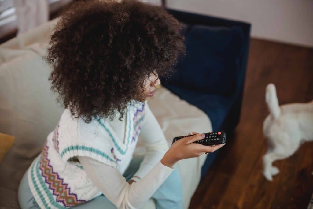 pexels-andres-ayrton-fille avec une télécommande - 7 signes que tu es accro aux séries