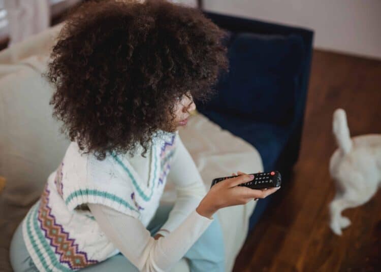 pexels-andres-ayrton-fille avec une télécommande - 7 signes que tu es accro aux séries