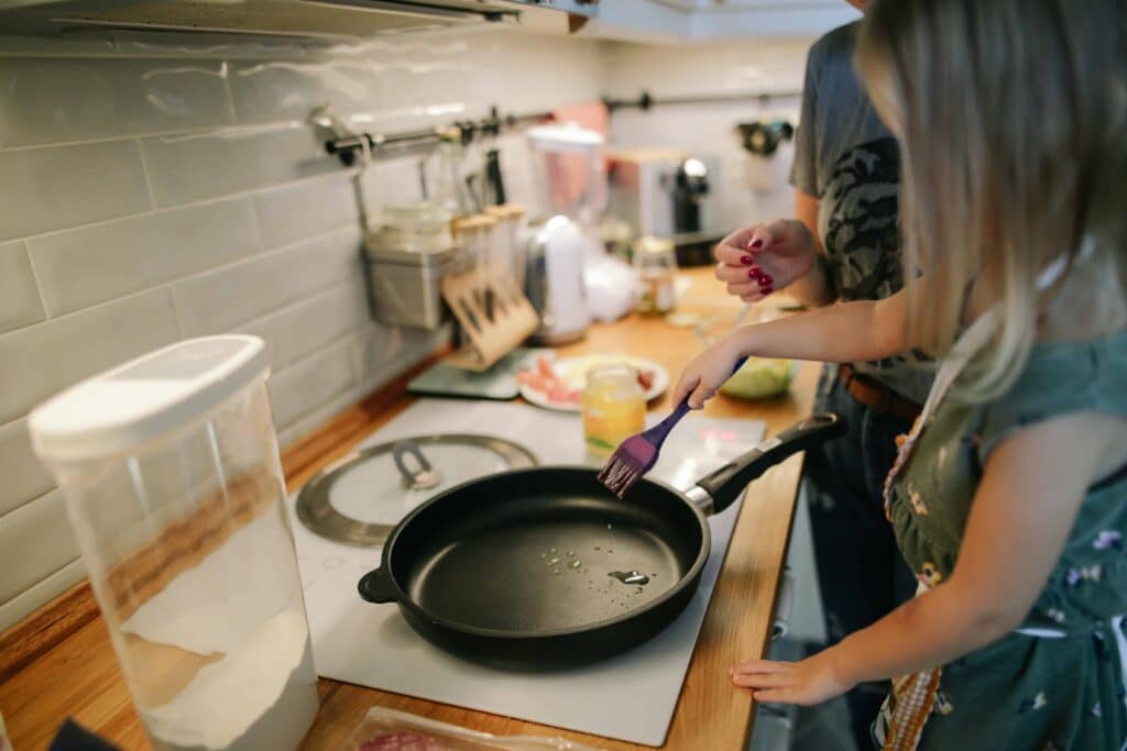 pexels-daria-obymaha-fille dans une cuisine avec une poele - top 10 des ustensiles de cuisine