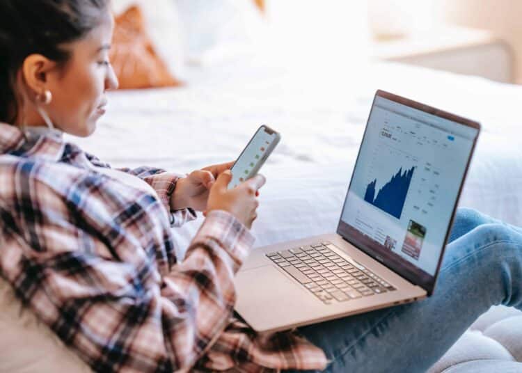pexels-liza-summer-femme sur son oridnateur et smarthpone - les jeunes plus actifs en bourse, la nouvelle côte ? -