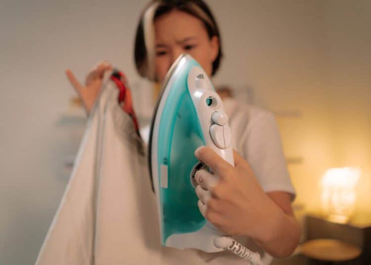 pexels-cottonbro-studio-jeune avec un fer à repasser-Comment ne plus avoir ses vêtements chiffonnés sans fer à repasser