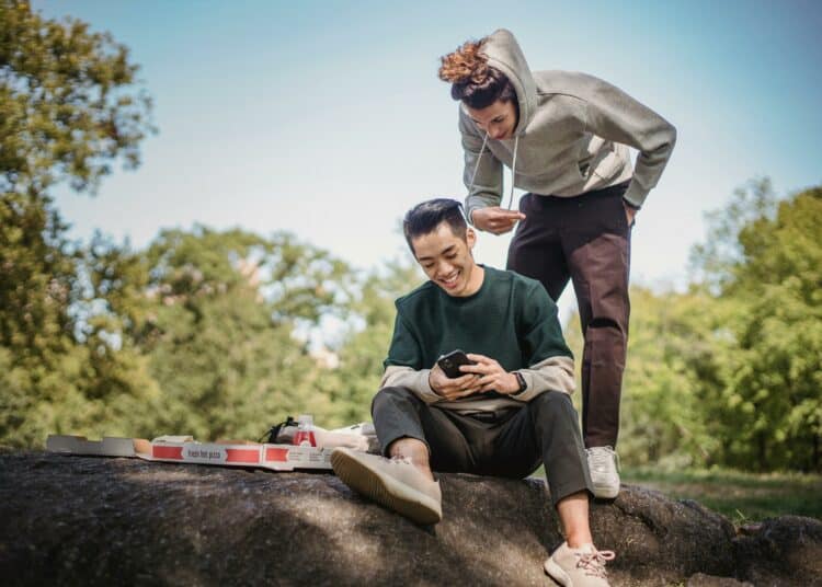 pexels-armin-rimoldi-jeunes assis dehors en train de regarder quelque chose sur un téléphone-Prévenir la diminution de la capacité de batterie de ton tel