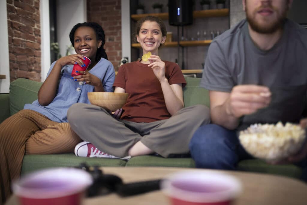 Freepik - Freepik - deux filles et un garçon sur un canapé regardant la tv - Les 6 classiques à voir pour décompresser après un exam