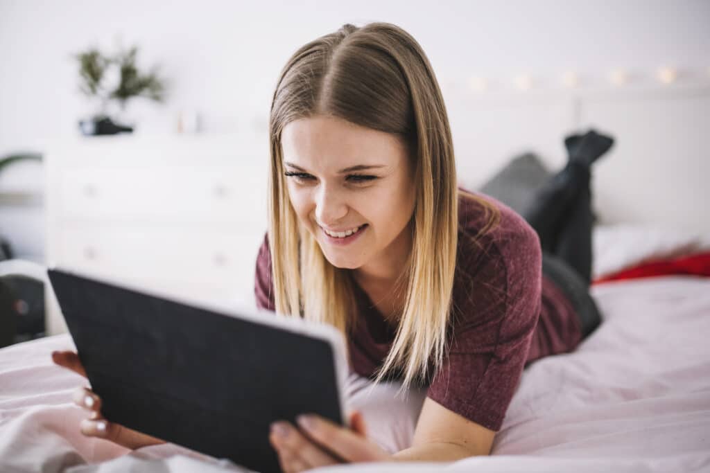 Freepik - freepik - fille qui sourit en regardant sa tablette - 4 séries à binge-watcher après ta session