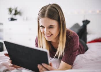 Freepik - freepik - fille qui sourit en regardant sa tablette - 4 séries à binge-watcher après ta session