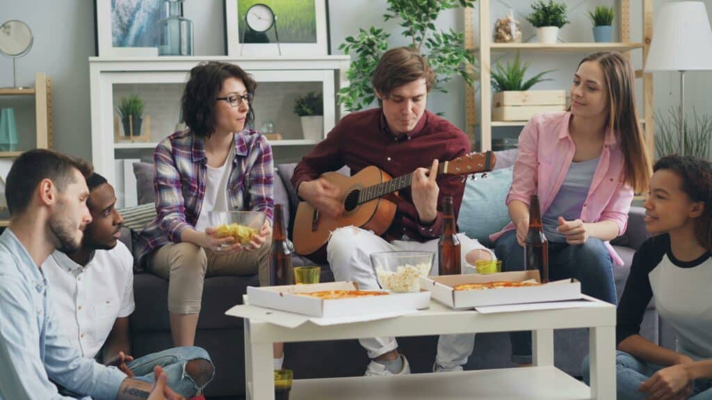 pexels-silverkblack-groupe de colocataire assis sur un divan et joueant de a guitare-7 façons de rendre votre coloc super chouette