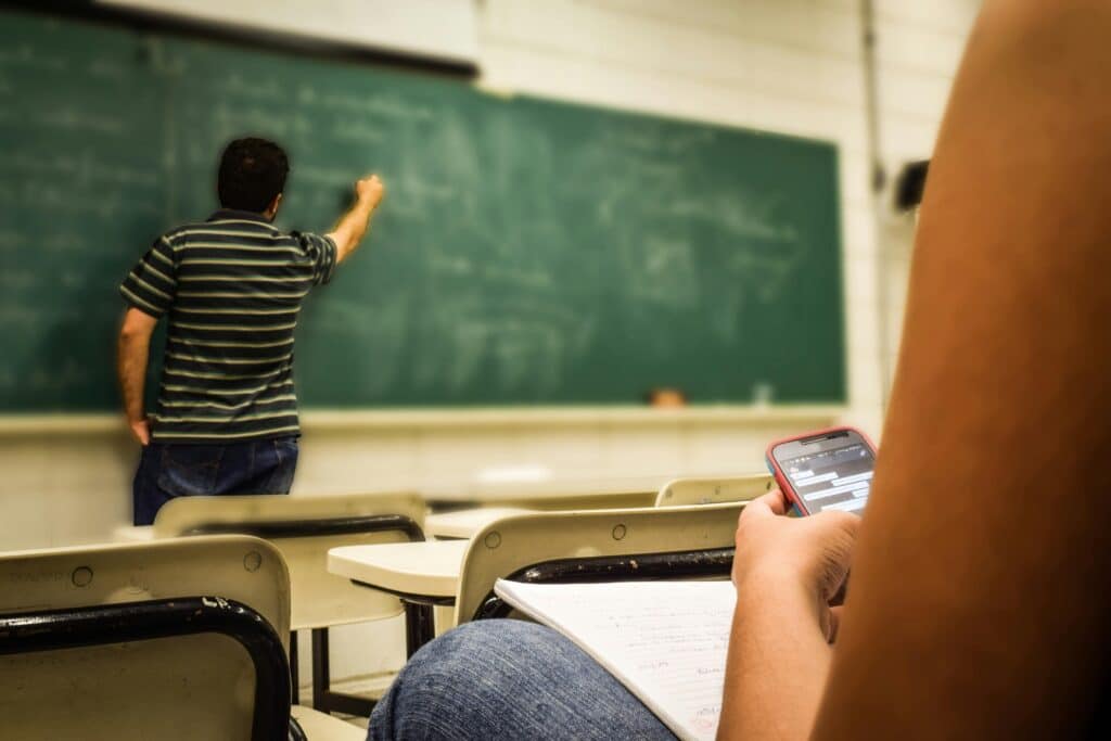 pexels-pixabay-avec qui donne cours en arrière plan et fille sur son téléphone en avant plan-7 astuces pour être productif pendant un cours
