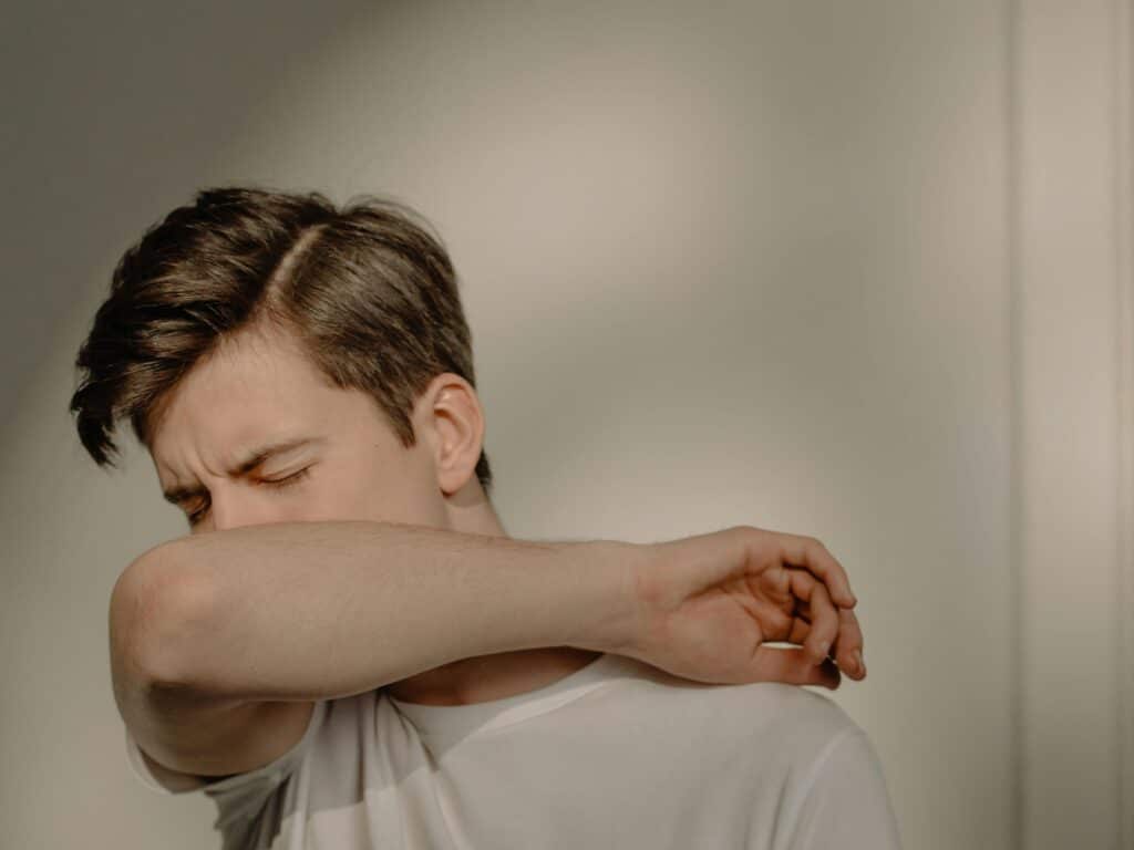 pexels-cottonbro-étudiant qui tousse dans son coude-Les 7 astuces de grands-mères pour guérir d’un rhume