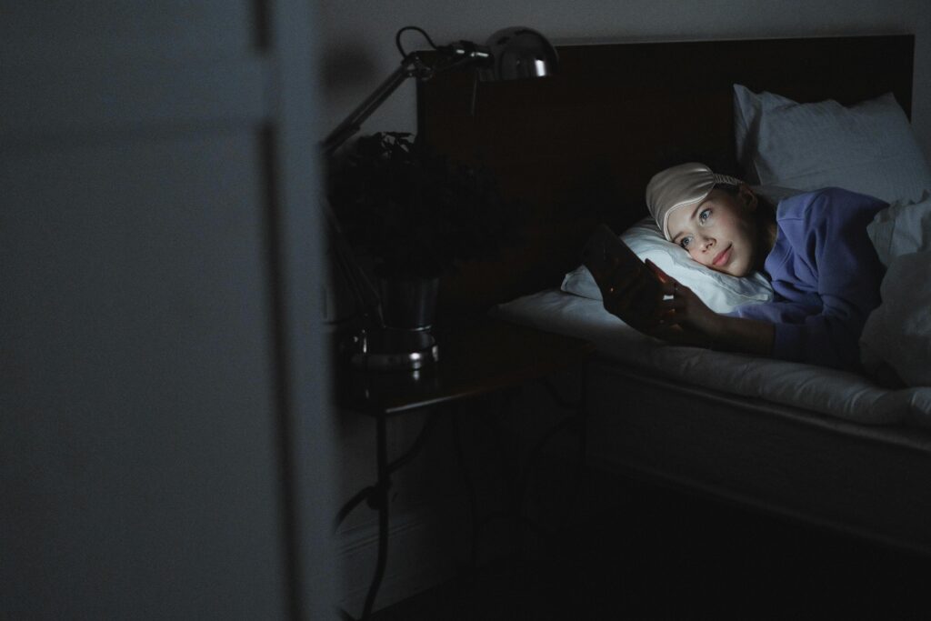 pexels-shvets-production-fille dans son lit avec son téléphone- La procrastination du sommeil, c'est quoi ?