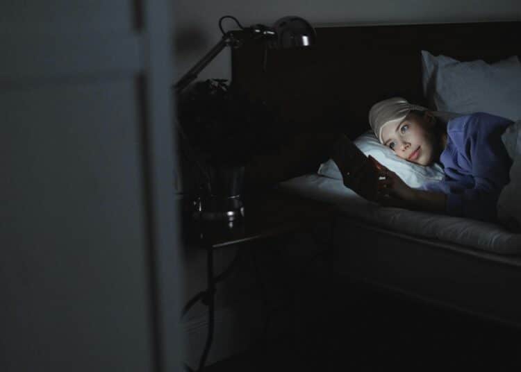 pexels-shvets-production-fille dans son lit avec son téléphone- La procrastination du sommeil, c'est quoi ?