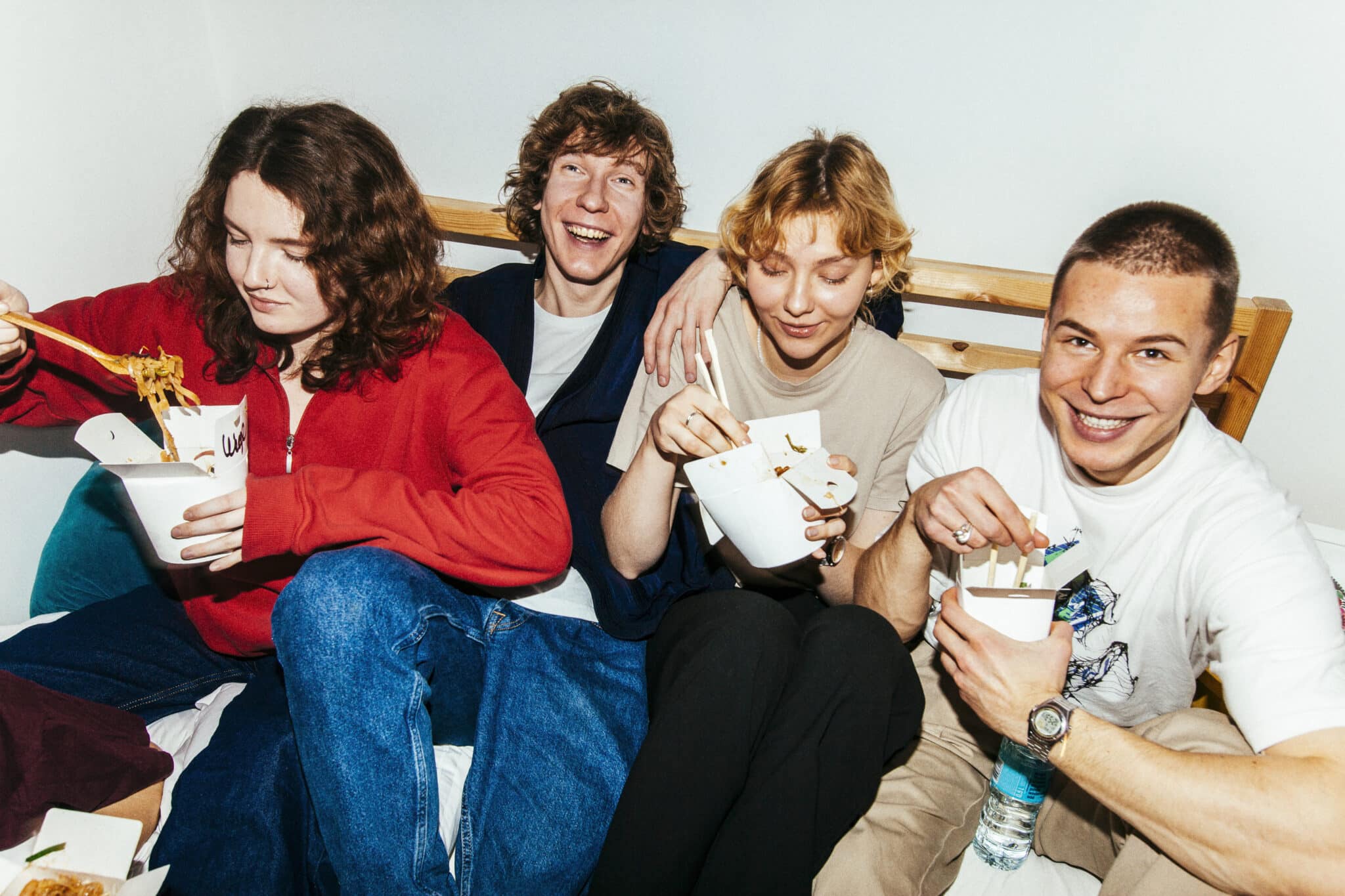Group of friends eating take away food from cartons in an apartment