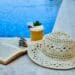 pexels-enginakyurt-lunette de soleil et chapeau et livre et cocktail au bord d'une piscine-8 vêtements indispensables pour slay en vacances