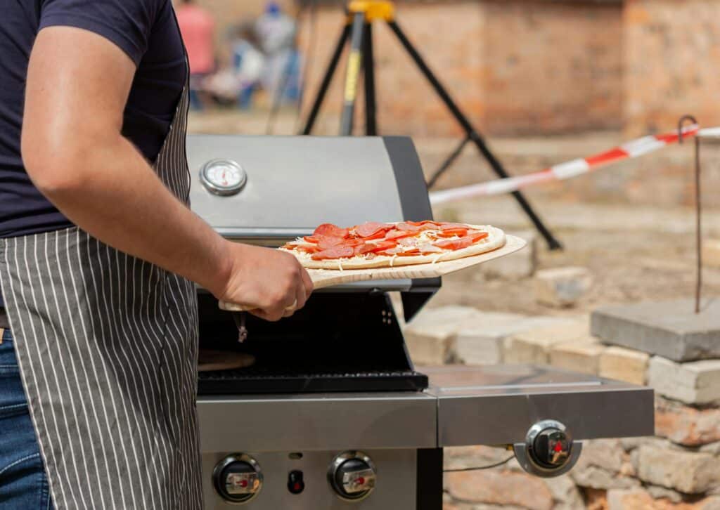 pexels-filirovska-personne qui met une pizza dans un barbecue-7 idées de repas pour un barbecue