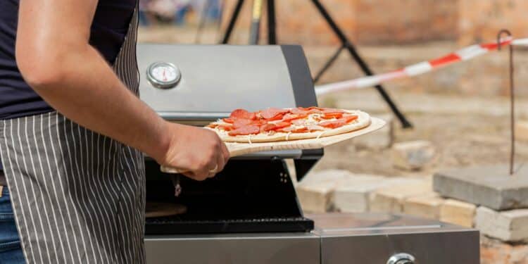 pexels-filirovska-personne qui met une pizza dans un barbecue-7 idées de repas pour un barbecue