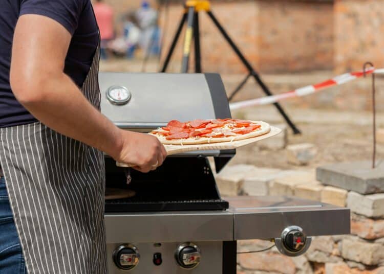 pexels-filirovska-personne qui met une pizza dans un barbecue-7 idées de repas pour un barbecue