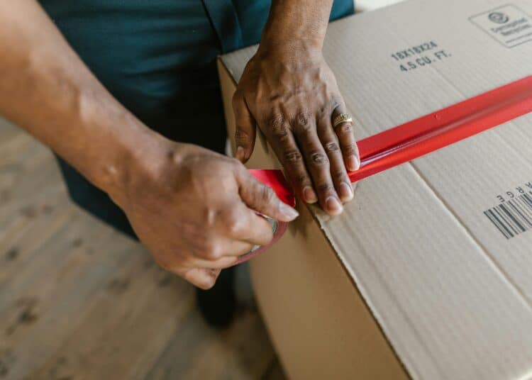 pexels-rdne-personne qui ferme un carton de déménagelent-10 indispensables à avoir dans son kot pour un premier aménagement