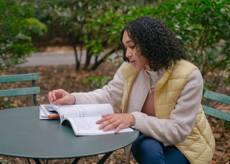 pexels-budgeron-bach-étudiante dehors qui étudie son syllabus-La deuxième session le dilemme entre étudier et profiter
