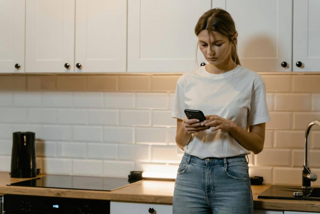 pexels-mart-production-étudiante sur son téléphoen dans la cuisine-C'est quoi le revenge porn ?