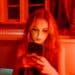pexels-mart-production-étudiante sur son téléphone dans une ambiance rouge triste-Que faire en Belgique si on est victime de revenge porn ?
