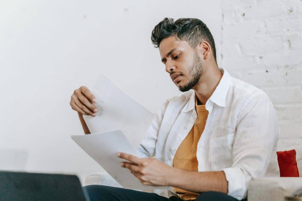 pexels-michael-burrows-jeune étudiant qui lit des feuilles assis sur le divan-7 aides financières que tu ne connaissais pas mais qui pourront t'aider