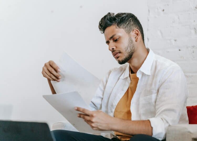 pexels-michael-burrows-jeune étudiant qui lit des feuilles assis sur le divan-7 aides financières que tu ne connaissais pas mais qui pourront t'aider