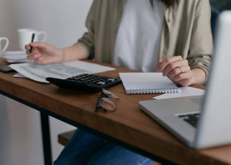pexels-mikhail-nilov-personne étudiante qui complète des documents sur un bureau-Comment bénéficier de l'allocation d'études en Fédération Wallonie-Bruxelles ?